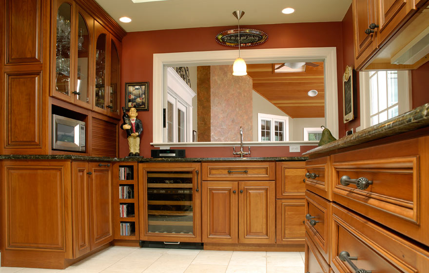 The long, angular layout and adjoining bar area provide ample cabinet storage while the cherry wood and yellow painted cabinetry pair perfectly.