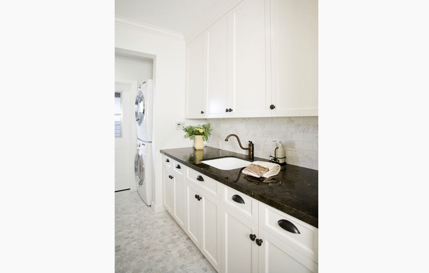 The light, neutral colors of this laundry area,contrast nicely with dark granite and traditional hardware.